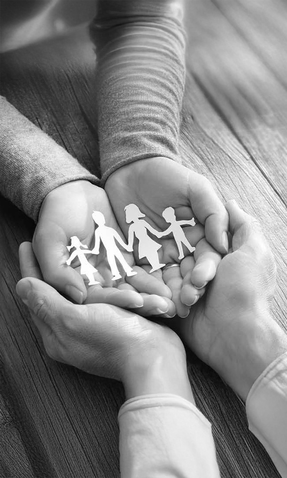Black-and-white image of hands holding cut-out figures of a family as a symbol of social engagement.