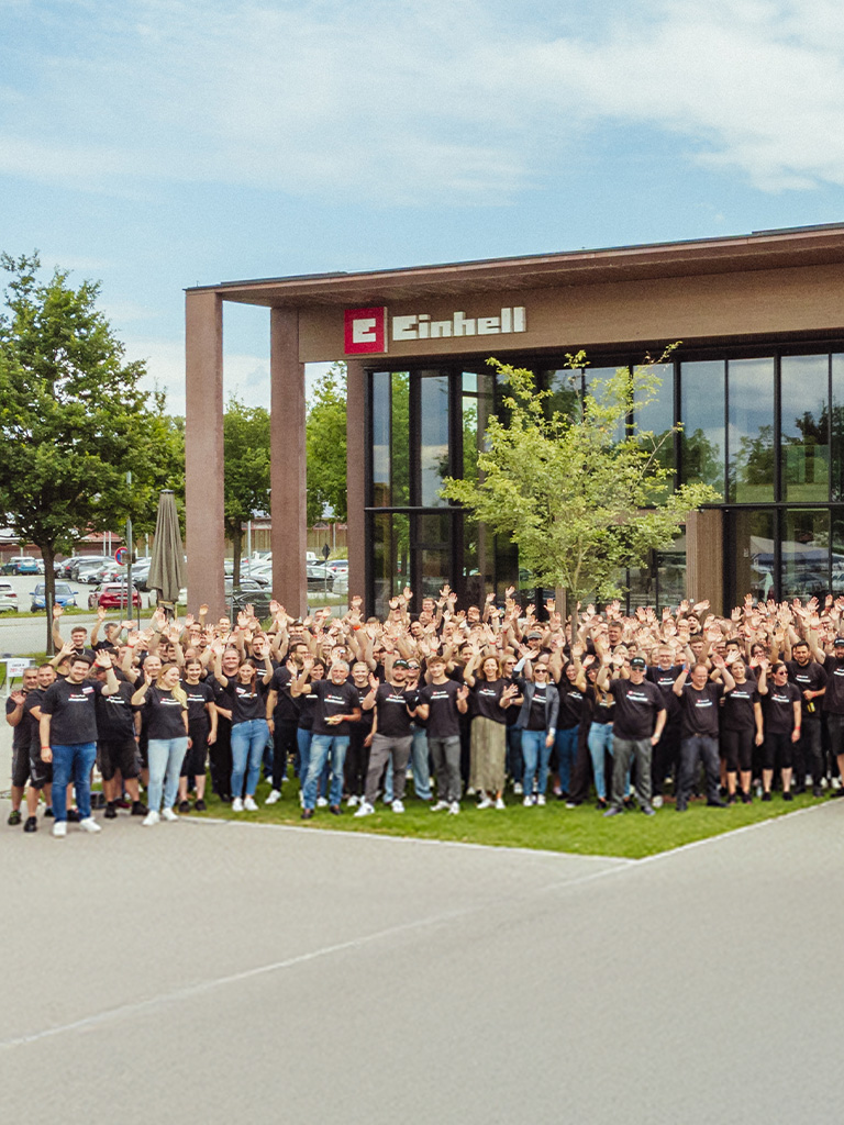 Einhell World: modern company building with Einhell logo and a large group of employees.