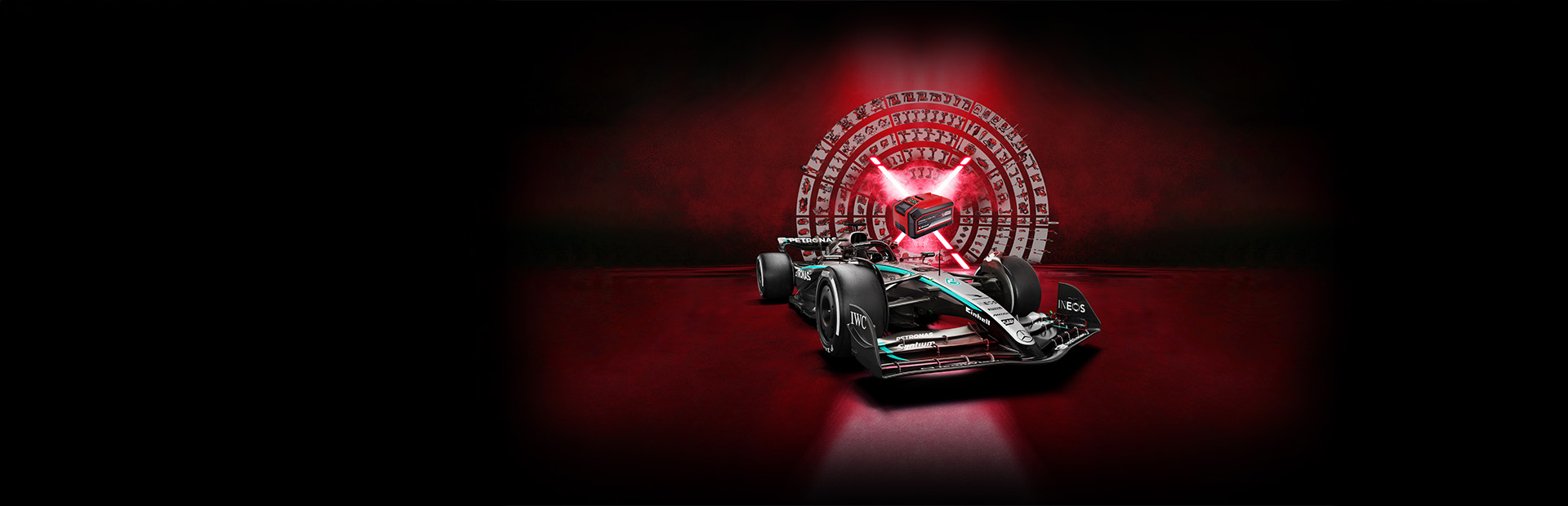 Un auto de carreras de Fórmula 1 Mercedes-AMG PETRONAS frente a un fondo rojo con una batería Einhell Power X-Change en el centro iluminada por rayos de luz rojos.