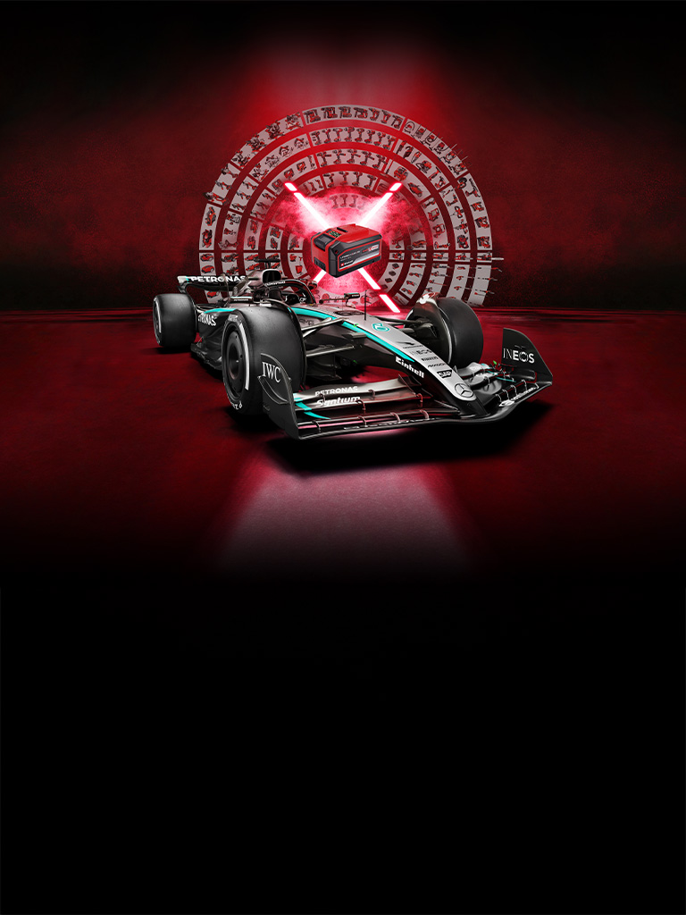 Un auto de carreras de Fórmula 1 Mercedes-AMG PETRONAS frente a un fondo rojo con una batería Einhell Power X-Change en el centro iluminada por rayos de luz rojos.