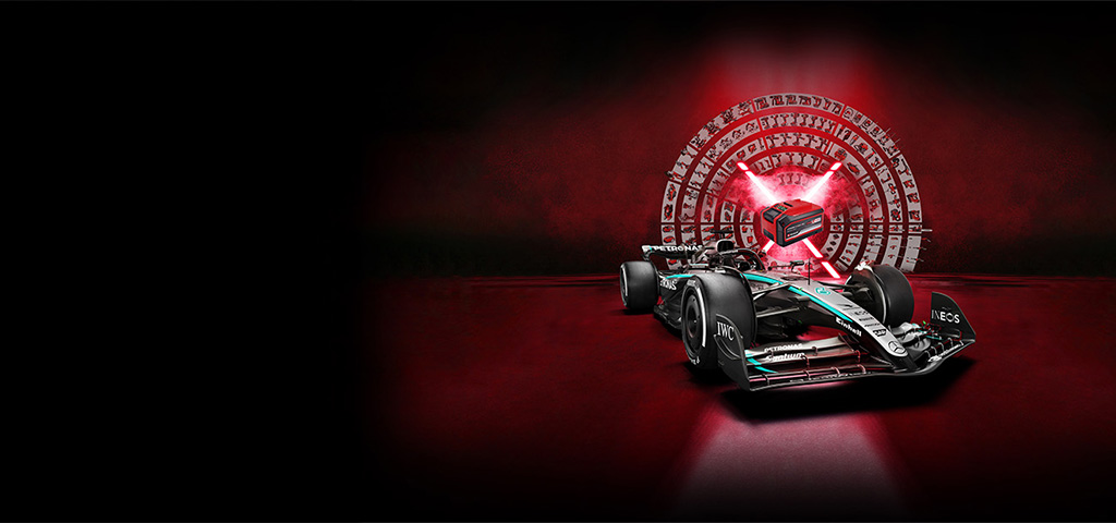 Un auto de carreras de Fórmula 1 aparece en primer plano sobre un fondo rojo oscuro. En el fondo, una batería estilizada Power X-Change luminosa está rodeada por un conjunto circular de herramientas e íconos de Einhell, que simbolizan potencia, tecnología y versatilidad.