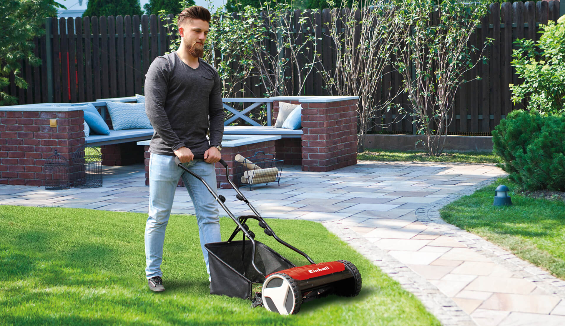 man with a hand lawn mower in garden