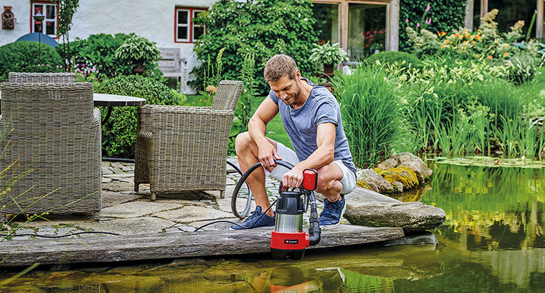 man using a submersible dirt water pump in a pond